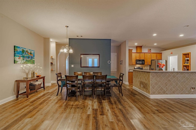 dining room featuring a chandelier, wood-type flooring, and a textured ceiling