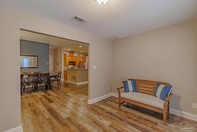 sitting room featuring light hardwood / wood-style floors and a textured ceiling