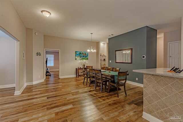 dining area featuring hardwood / wood-style flooring, a textured ceiling, and a chandelier