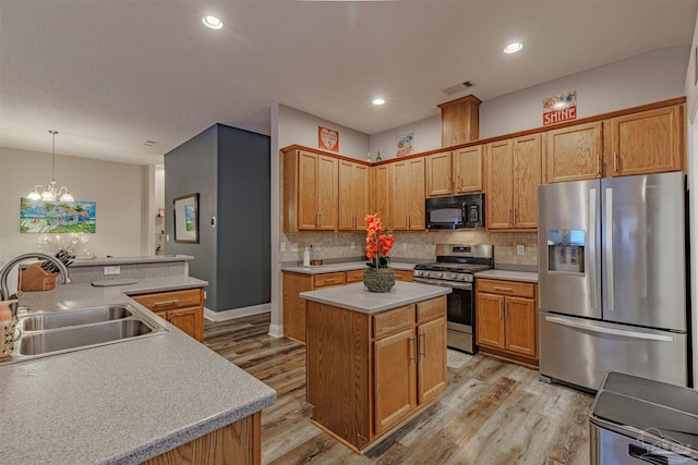 kitchen with appliances with stainless steel finishes, light wood-type flooring, sink, an inviting chandelier, and a kitchen island