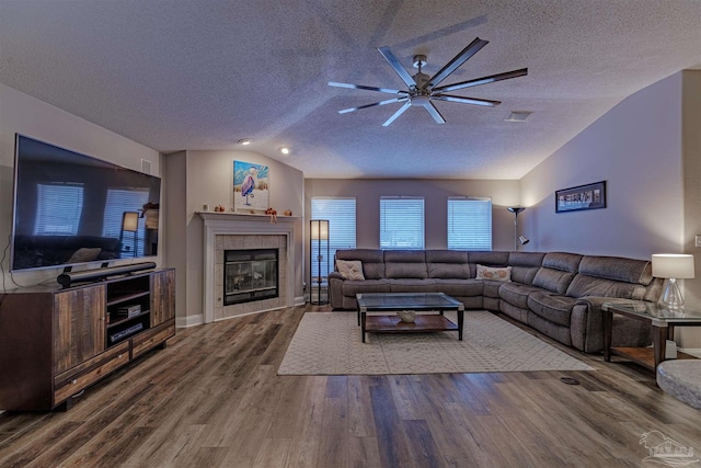 living room with lofted ceiling, wood-type flooring, a textured ceiling, and a tiled fireplace