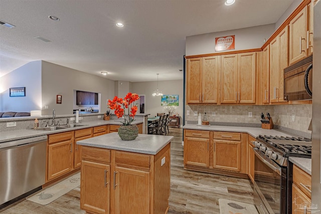 kitchen with sink, stainless steel appliances, light hardwood / wood-style flooring, a notable chandelier, and pendant lighting