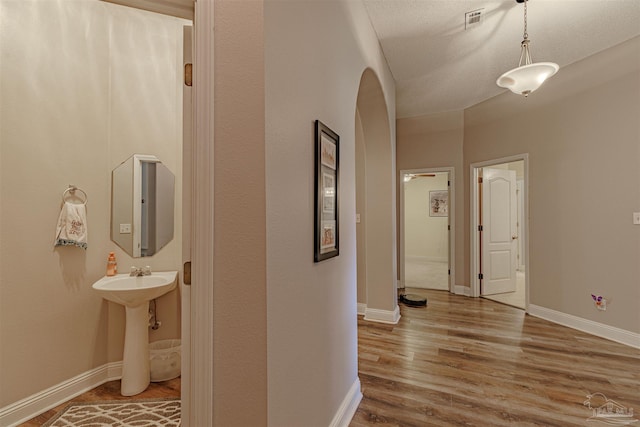 corridor with a textured ceiling and hardwood / wood-style flooring