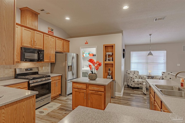 kitchen featuring sink, tasteful backsplash, light hardwood / wood-style floors, decorative light fixtures, and appliances with stainless steel finishes