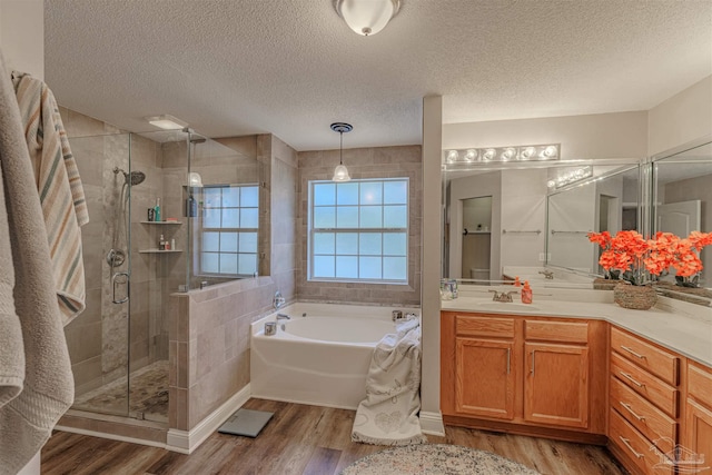 bathroom featuring separate shower and tub, vanity, wood-type flooring, and a textured ceiling