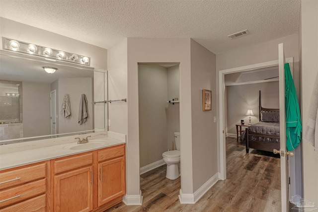 bathroom with hardwood / wood-style flooring, vanity, toilet, and a textured ceiling