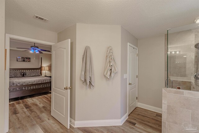 bathroom with hardwood / wood-style floors, a textured ceiling, and a shower with door