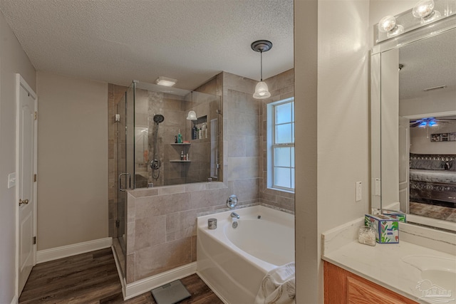 bathroom with vanity, wood-type flooring, a textured ceiling, and shower with separate bathtub