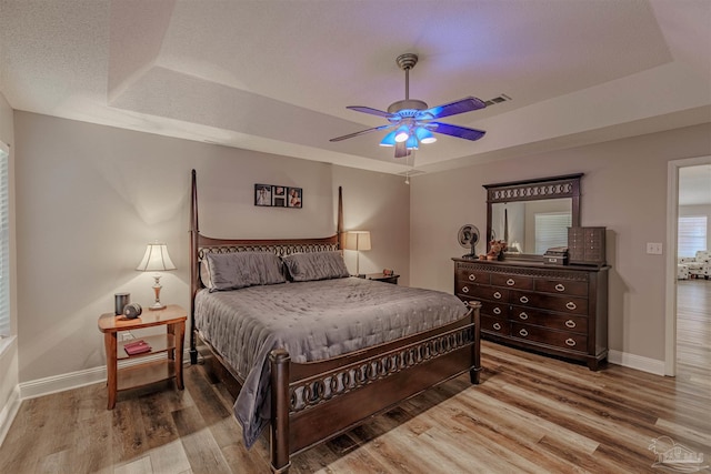 bedroom featuring ceiling fan, a raised ceiling, and wood-type flooring