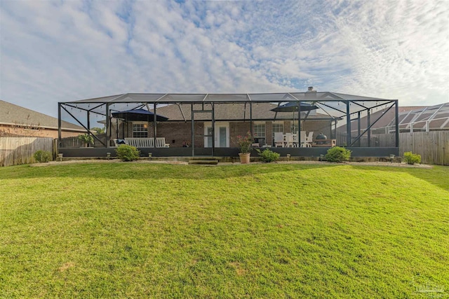 rear view of house with a lanai and a lawn