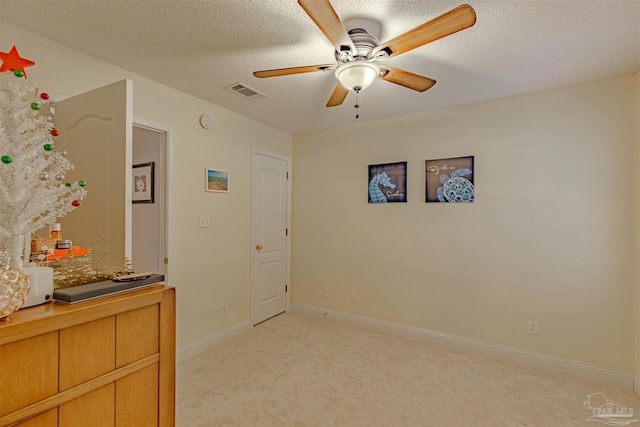 interior space with ceiling fan, light colored carpet, and a textured ceiling