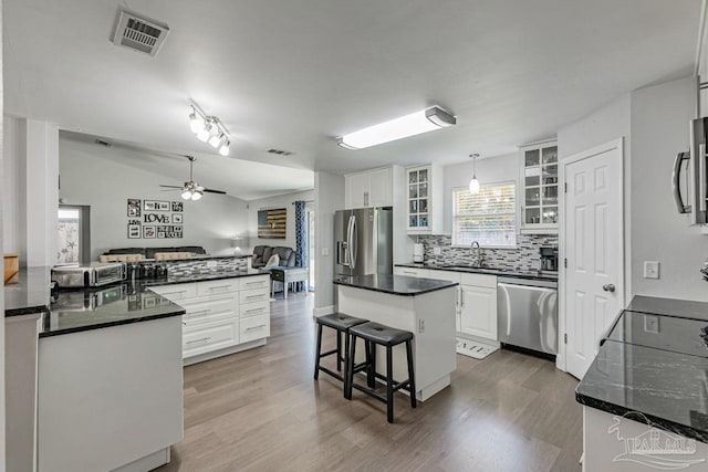 kitchen with white cabinets, appliances with stainless steel finishes, sink, pendant lighting, and a center island