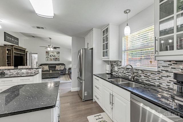 kitchen with appliances with stainless steel finishes, sink, white cabinetry, vaulted ceiling, and decorative light fixtures