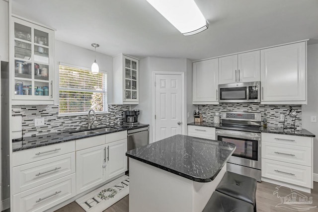 kitchen with a kitchen island, stainless steel appliances, sink, white cabinetry, and tasteful backsplash