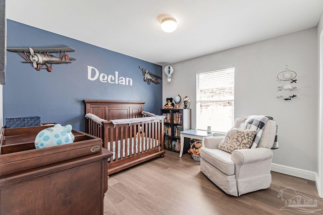 bedroom featuring a nursery area and light wood-type flooring