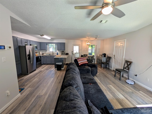 living room with ceiling fan with notable chandelier, a textured ceiling, hardwood / wood-style flooring, and lofted ceiling