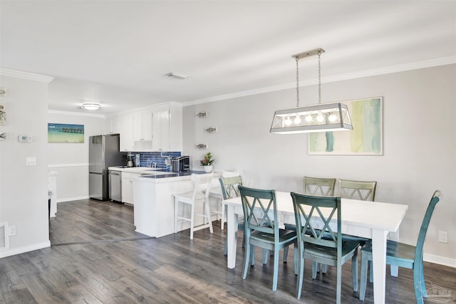 kitchen featuring white cabinetry, stainless steel appliances, kitchen peninsula, decorative light fixtures, and a breakfast bar