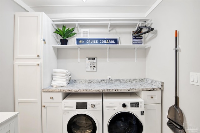 clothes washing area featuring cabinets and washing machine and dryer