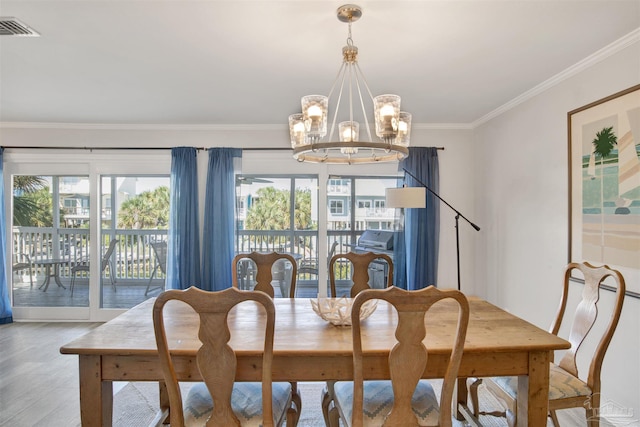 dining area featuring ornamental molding, light wood-type flooring, and a notable chandelier