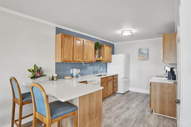 kitchen featuring a breakfast bar, white appliances, crown molding, light hardwood / wood-style floors, and kitchen peninsula