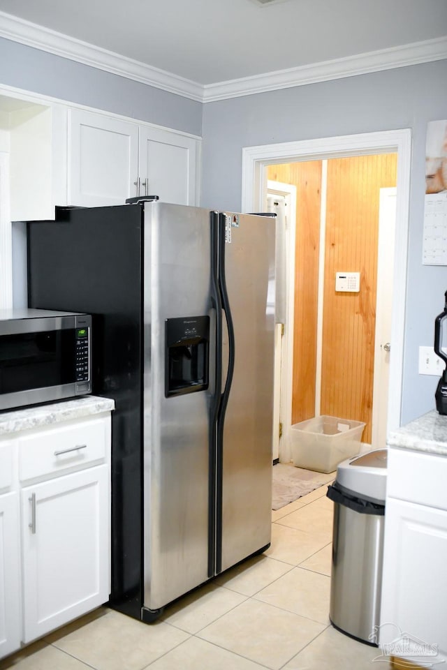 kitchen with light tile patterned floors, appliances with stainless steel finishes, crown molding, and white cabinetry