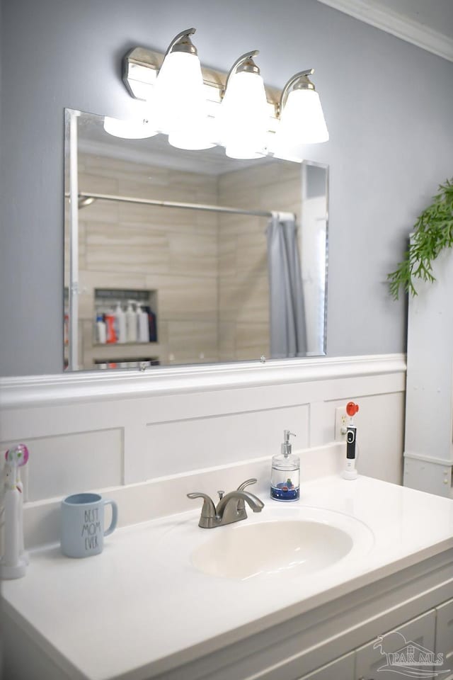 bathroom with vanity, curtained shower, and ornamental molding