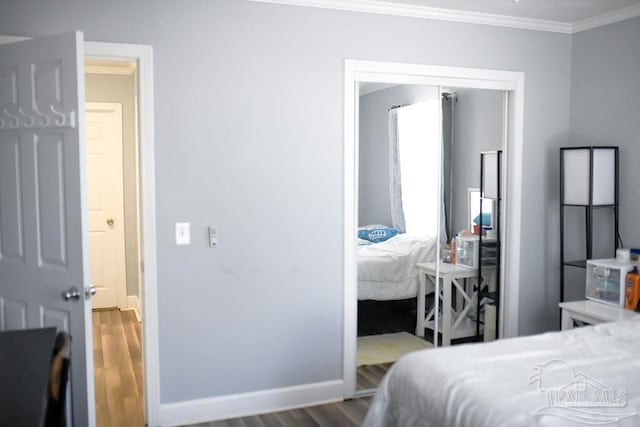 bedroom featuring baseboards, wood finished floors, and ornamental molding