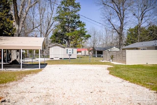 view of yard with a detached carport, an outbuilding, and fence