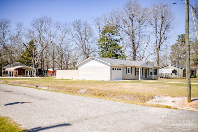 view of front of property featuring a detached carport, a front yard, fence, driveway, and an attached garage