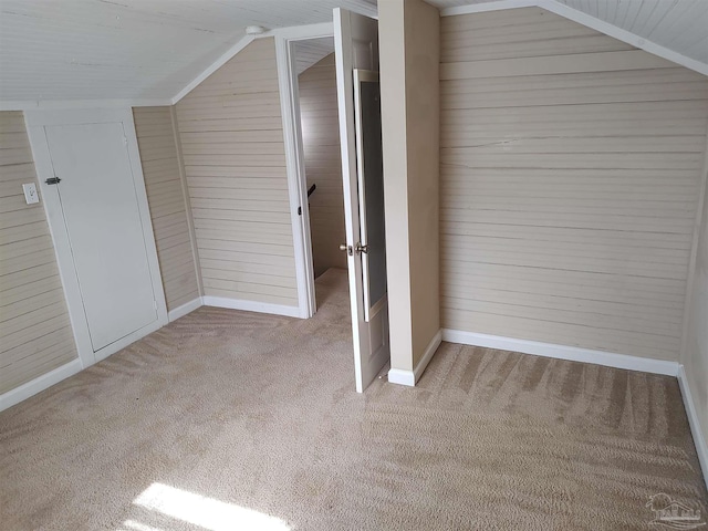 bonus room featuring light colored carpet, lofted ceiling, and wooden walls