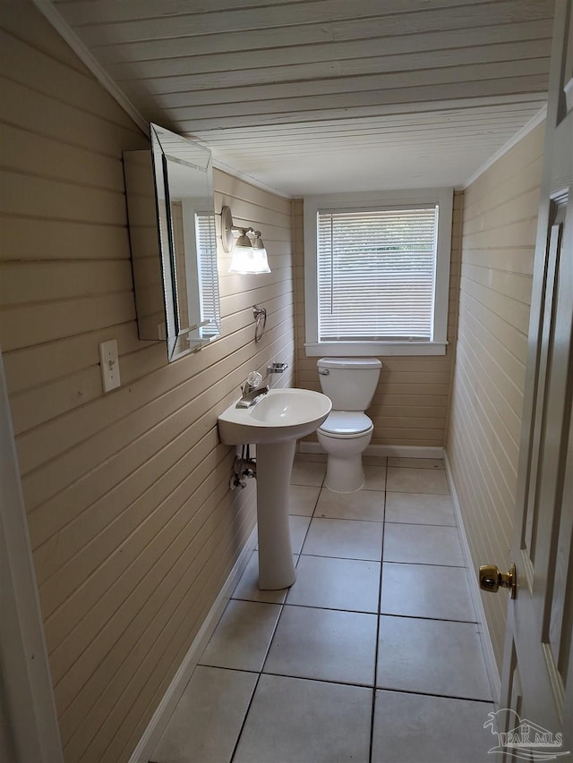 bathroom with wood walls, ornamental molding, tile patterned floors, and toilet