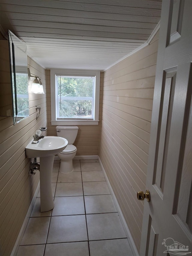 bathroom featuring wooden walls, tile patterned floors, toilet, and sink