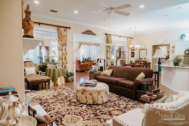 living room featuring hardwood / wood-style flooring, ornamental molding, and ceiling fan with notable chandelier