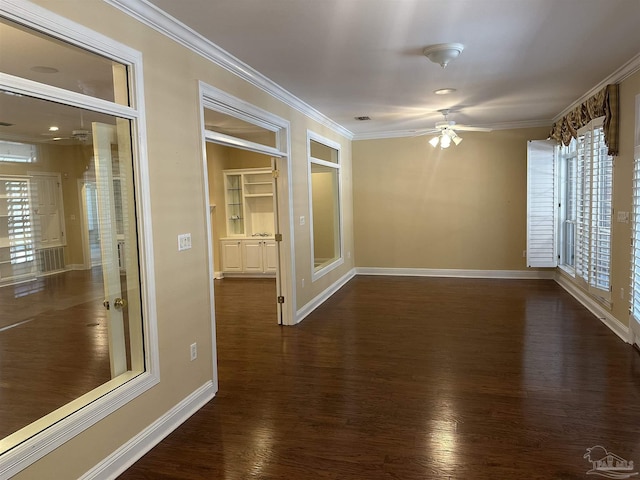 spare room featuring dark wood finished floors, crown molding, and baseboards