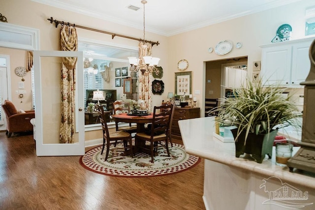 dining room with an inviting chandelier, crown molding, and dark wood-type flooring