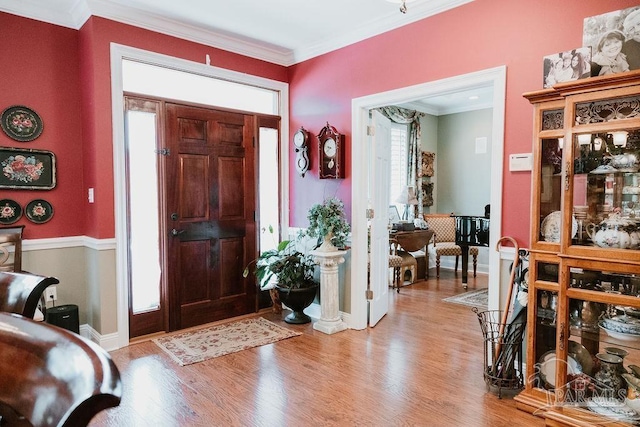 foyer with ornamental molding, light wood-style flooring, and baseboards