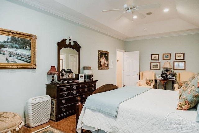 bedroom featuring ceiling fan, a tray ceiling, ornamental molding, and light hardwood / wood-style flooring