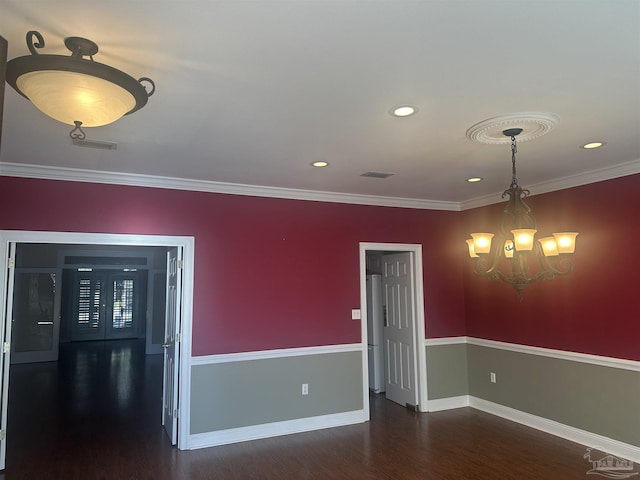 unfurnished room with wood finished floors, visible vents, baseboards, ornamental molding, and an inviting chandelier