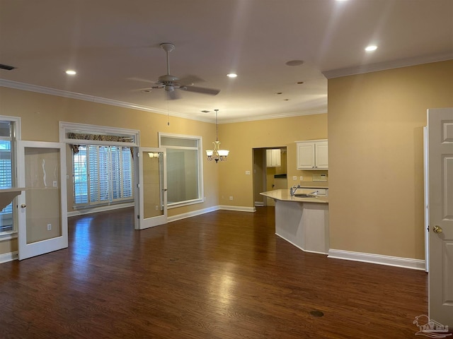 unfurnished living room with ornamental molding, dark wood-type flooring, ceiling fan with notable chandelier, and sink