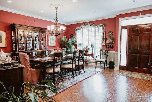 dining space with ornamental molding, a chandelier, and wood-type flooring