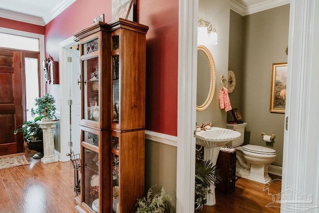 interior space with toilet, hardwood / wood-style flooring, and ornamental molding