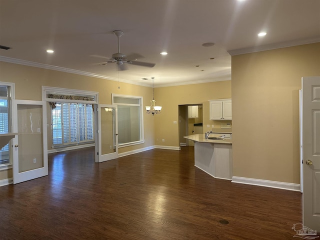 unfurnished living room featuring ceiling fan with notable chandelier, a sink, baseboards, dark wood-style floors, and crown molding