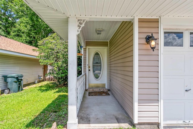 view of exterior entry with a garage and a lawn