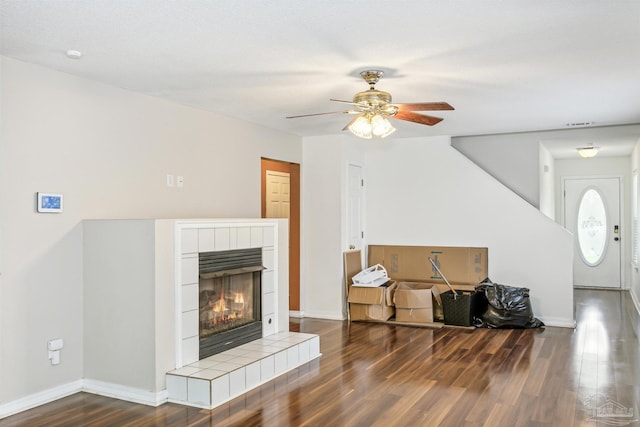 living room with a fireplace, ceiling fan, and dark wood-type flooring