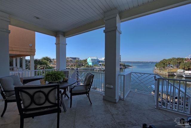 view of patio / terrace with a water view, a balcony, and outdoor dining space