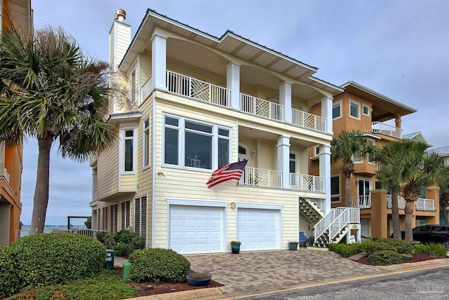 view of front of property with a garage, decorative driveway, a chimney, and a balcony