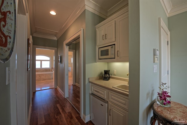 kitchen featuring dark wood-style floors, light countertops, white microwave, ornamental molding, and a sink