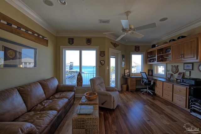 living room with ceiling fan, dark wood-style flooring, a water view, visible vents, and ornamental molding