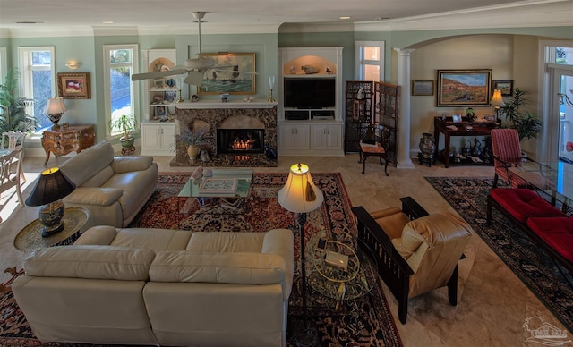 living room featuring built in features, a fireplace, decorative columns, and crown molding