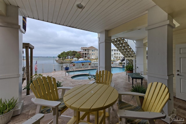 balcony with a patio area, a water view, and a hot tub